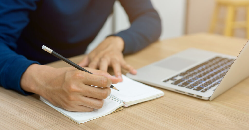 SEO Texter - Laptop und Heft auf dem Tisch
